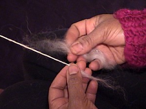 Adding more fiber to spun yarn.