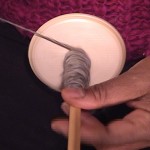 Winding yarn onto a bottom whorl drop spindle.