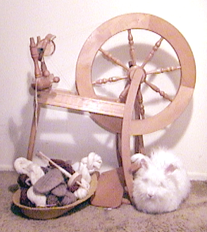 Scene of a basket of handspun yarn, spinning wheel, and Jaleebi.